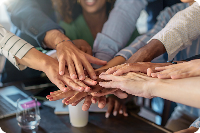 A group of people zoomed in on their hands stacked on top of each other about to do hands-in team cheer. 